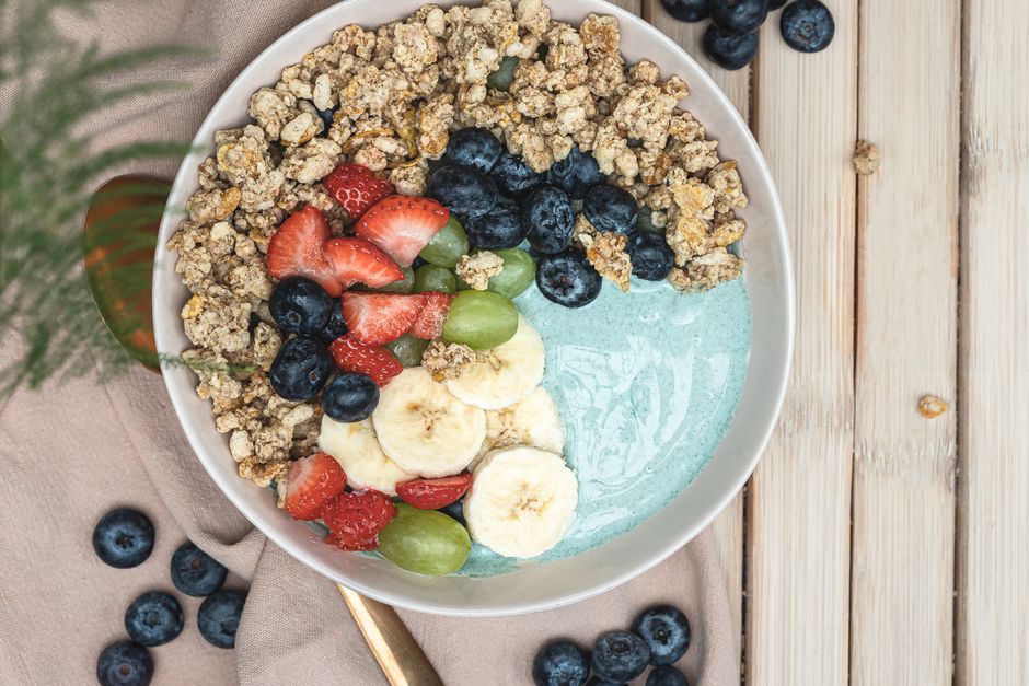 A delicious smoothie bowl topped with granola, fresh berries, and banana slices on a wooden table.